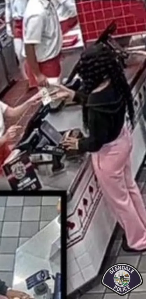 Surveillance image of a person in pink pants exchanging counterfeit currency at a counter.