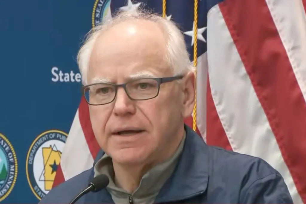 Gov. Tim Walz speaking in front of an American flag and a state seal.