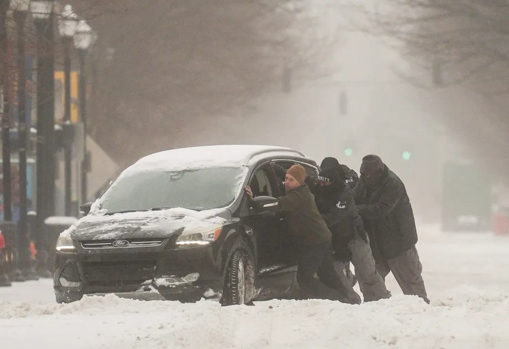 A group of men attempting to help a driver stuck in the snow in Louisville.