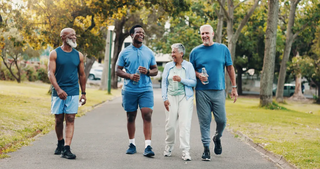 Four smiling adults walking outdoors in a park
