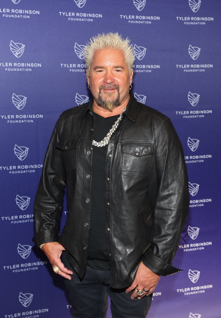 Guy Fieri standing in front of a purple backdrop with the Tyler Robinson Foundation logo.