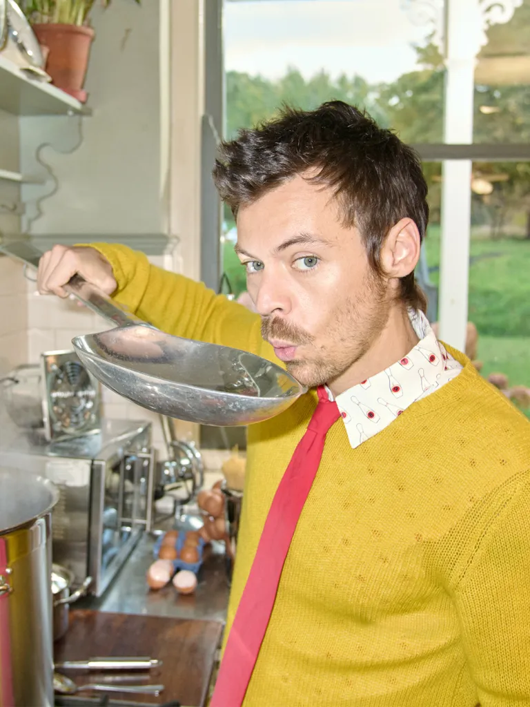 Harry Styles tasting from a large spoon while cooking.