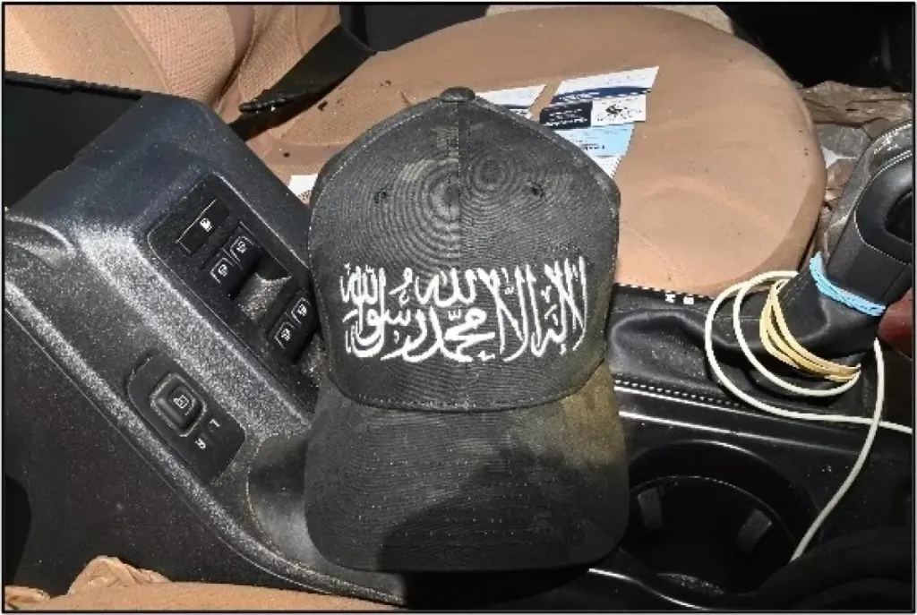 A black baseball cap with white Arabic calligraphy resembling the Al Qaeda flag.