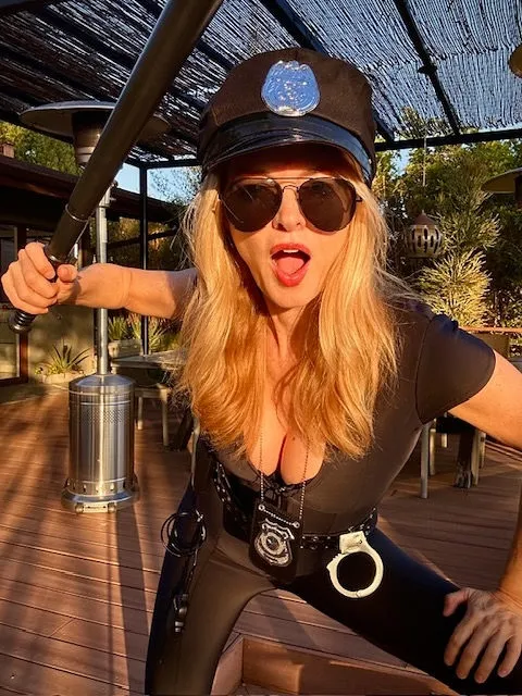 Heather Graham in a police uniform, holding a baton.