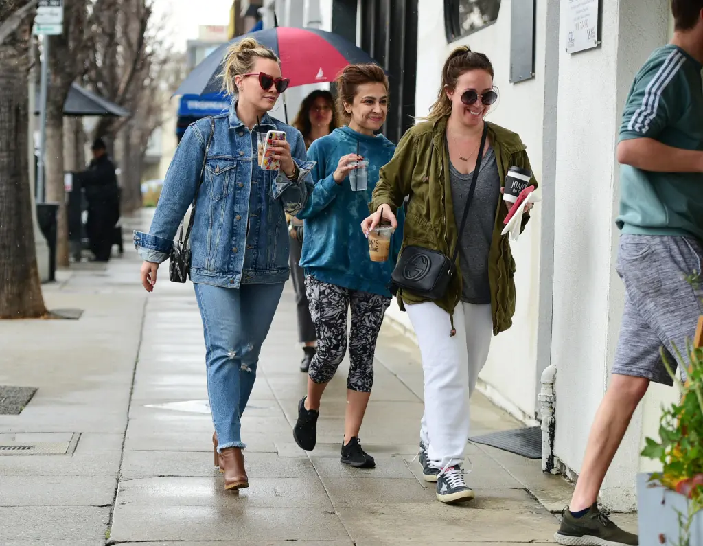Hilary and Haylie Duff walking down the street with beverages.