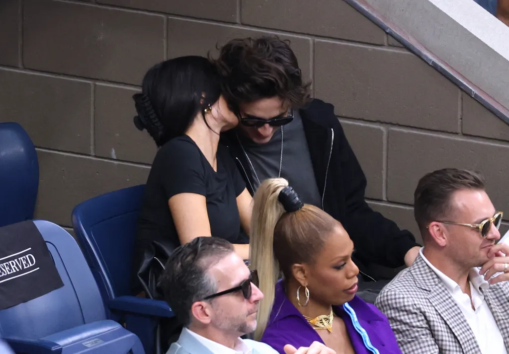 Kylie Jenner leaning in towards Timothee Chalamet at the US Open, with Laverne Cox seated in the foreground.