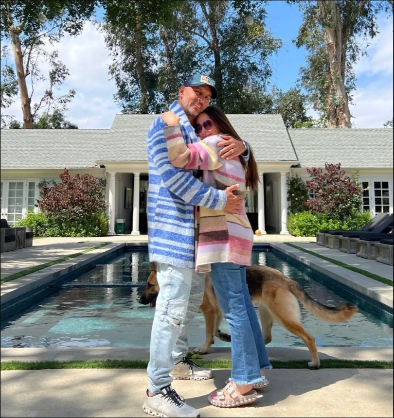Kyle Richards and Mauricio Umansky embracing outside their home with a pool and a dog.