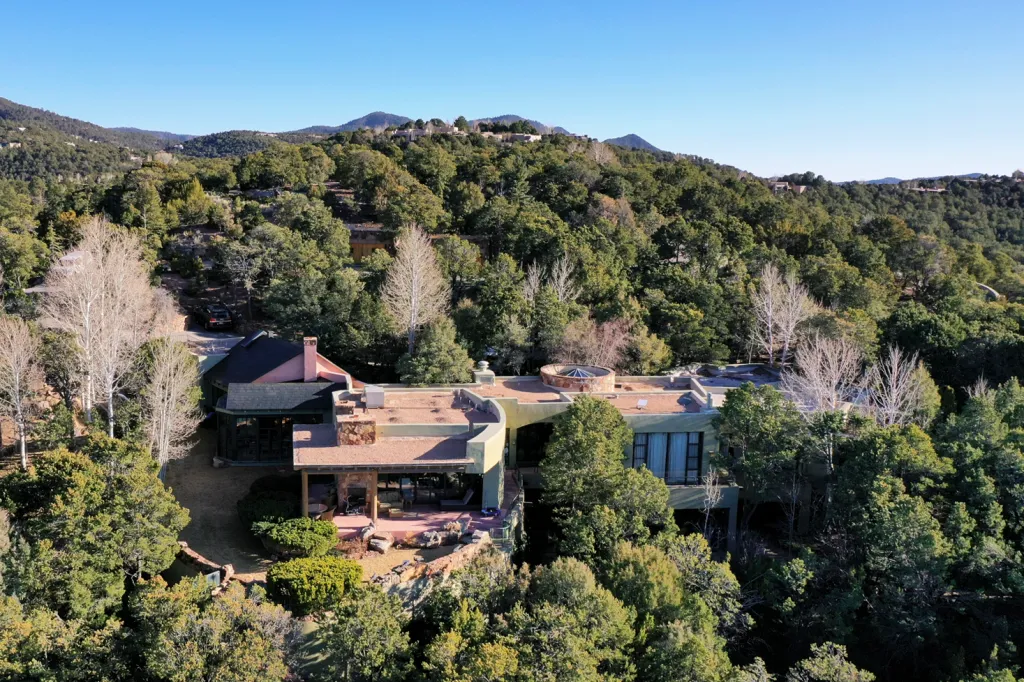Aerial view of actor Gene Hackman's house in Santa Fe, New Mexico, surrounded by lush green trees and distant mountains.