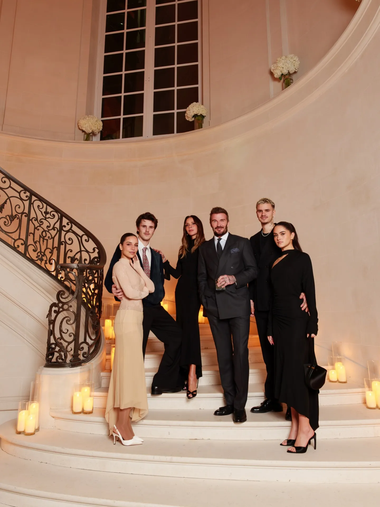 Victoria and David Beckham and their children pose for a family photo on a grand staircase lit with candles.