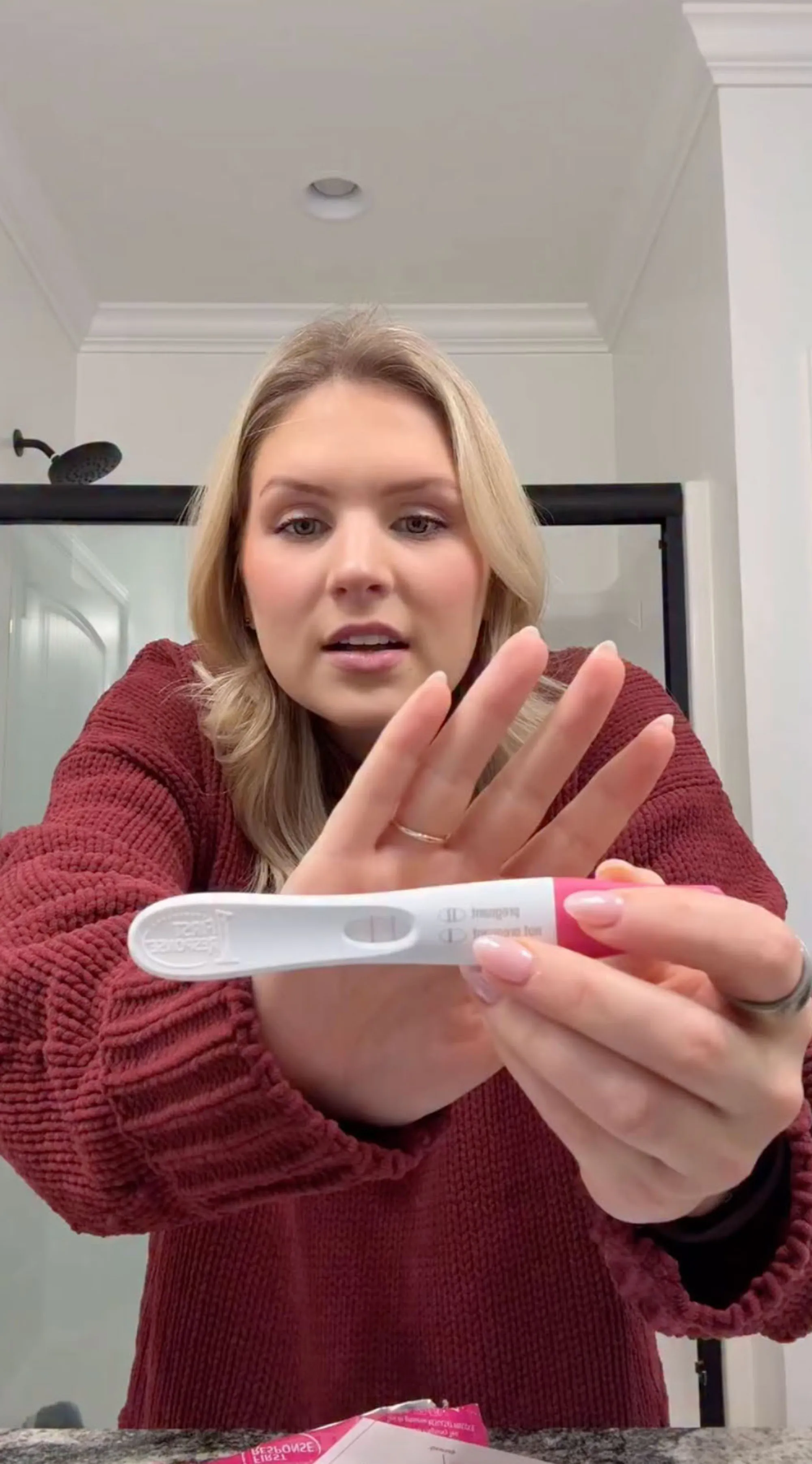 A woman in a red sweater holds up a positive pregnancy test.