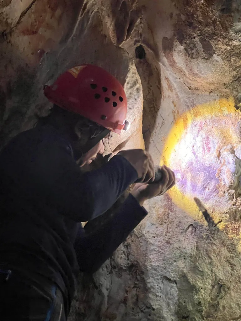 Researcher shining a light on cave art.