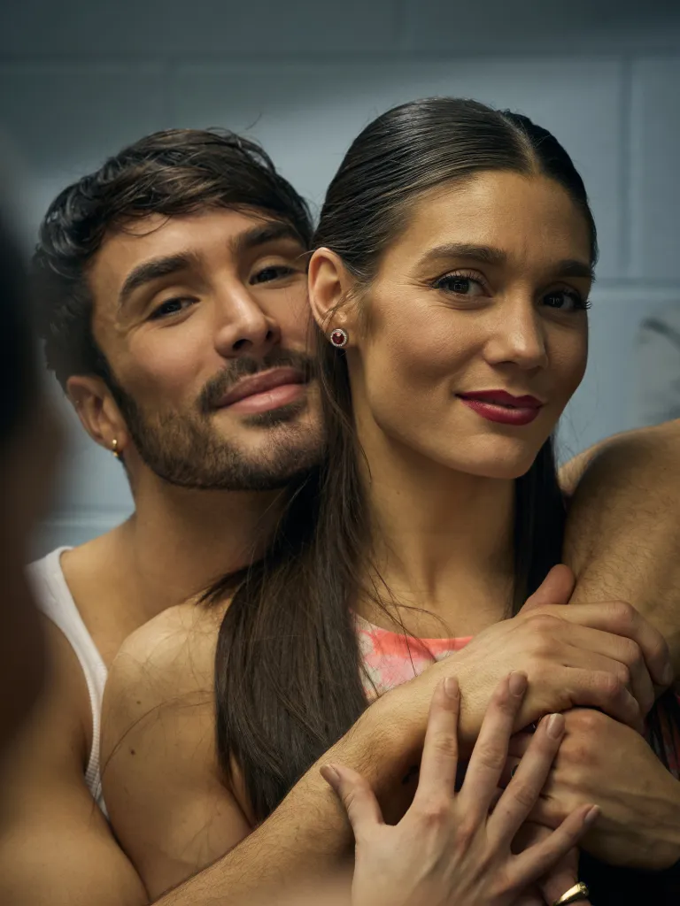 Portrait of ice dancers Laurence Fournier Beaudry and Guillaume Cizeron with his arms wrapped around her.