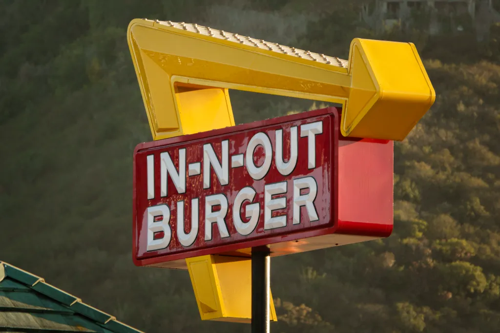 The In-N-Out Burger logo sign, with a red sign and white lettering, featuring a yellow arrow pointing right.