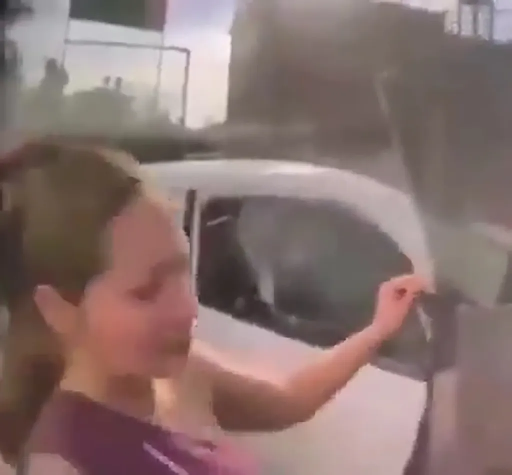 Woman looking into the car and trying to open the door.