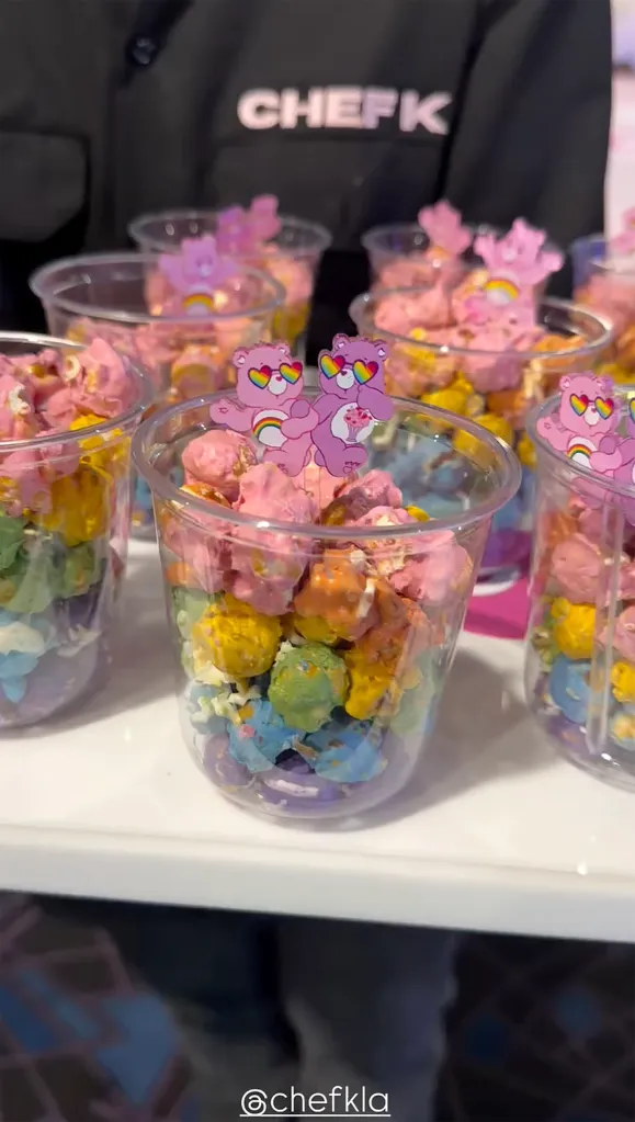 Clear plastic cups filled with rainbow-colored popcorn, topped with pink Care Bear cutouts.