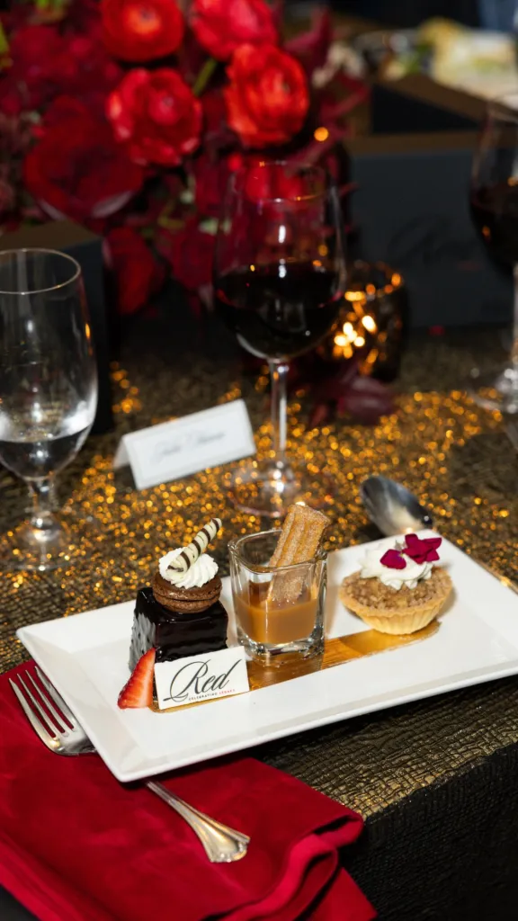 Dessert plate with a slice of dark chocolate cake, churros in a glass of dulce de leche, and a pecan tart.