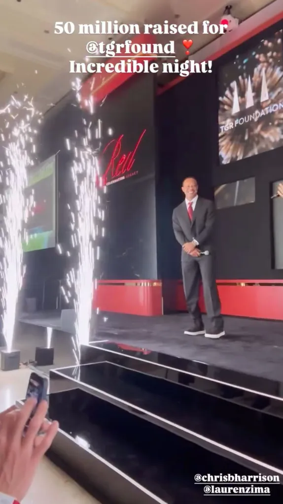 Tiger Woods on stage in a suit and tie, with pyrotechnics, celebrating 