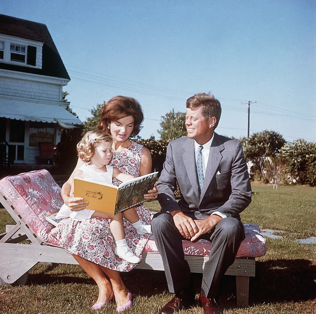 Jacqueline Kennedy reading to her daughter Caroline, with John F. Kennedy beside them, at their summer home.