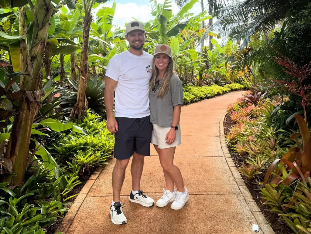 Jana Duggar and Stephen Wissmann standing on a path surrounded by tropical plants.