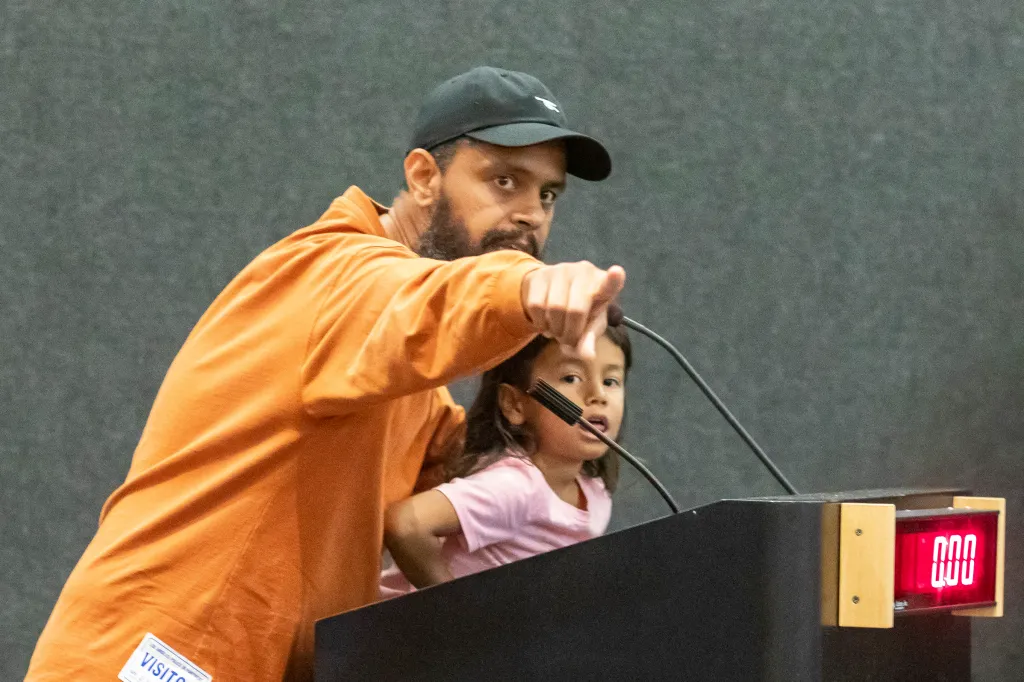 Jason Reedy, accompanied by a young girl, speaks during a meeting.
