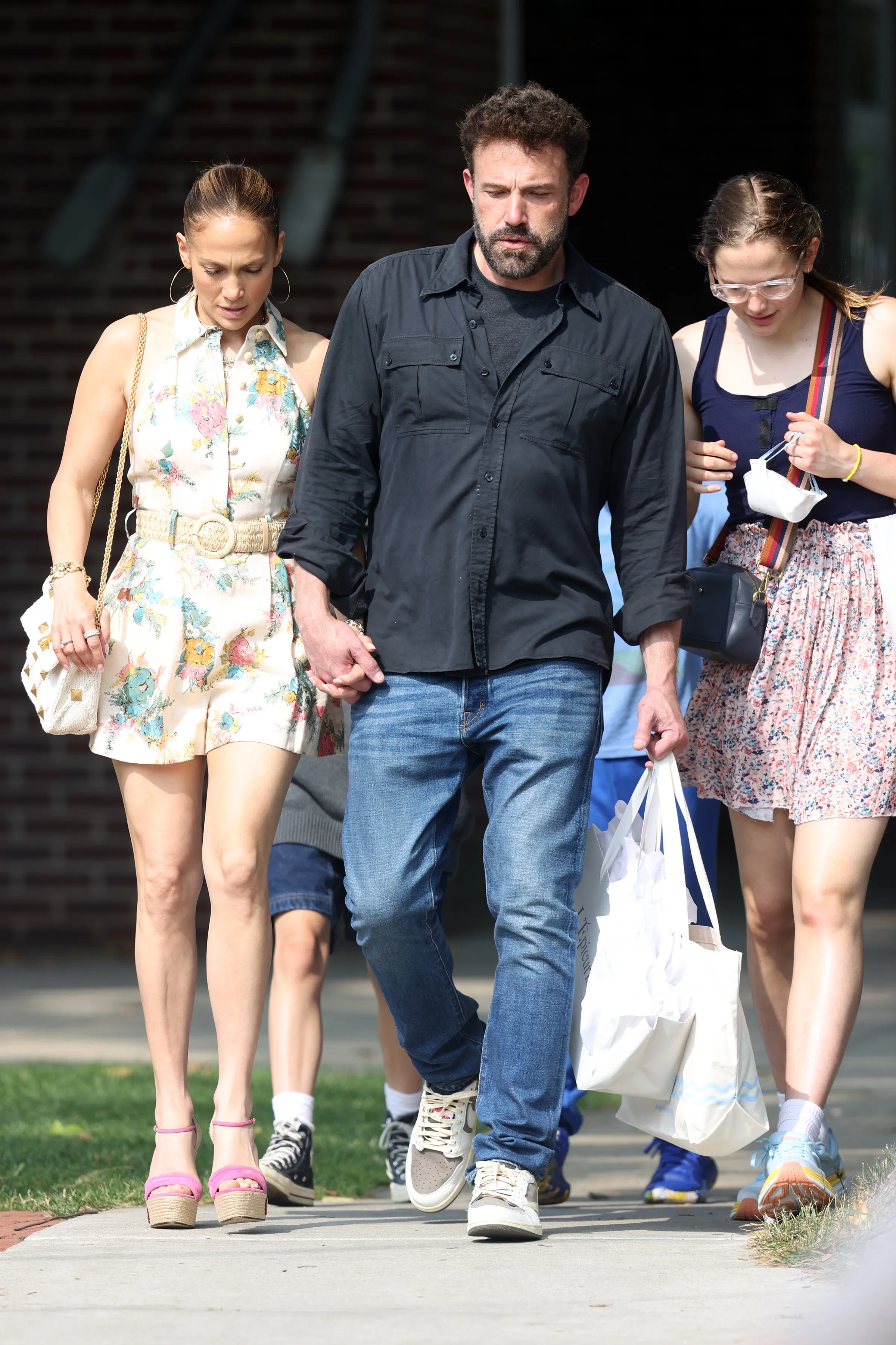 Jennifer Lopez and Ben Affleck holding hands while walking with Ben's daughter Violet.
