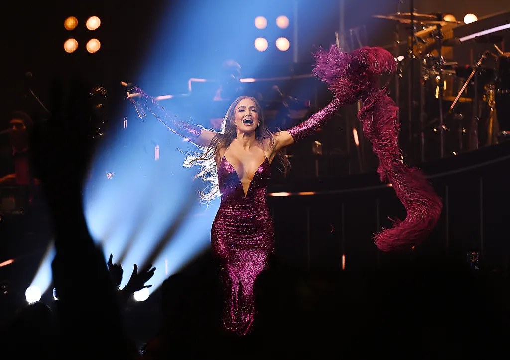 Jennifer Lopez performs in a shimmering fuchsia gown and long feathered sleeves.