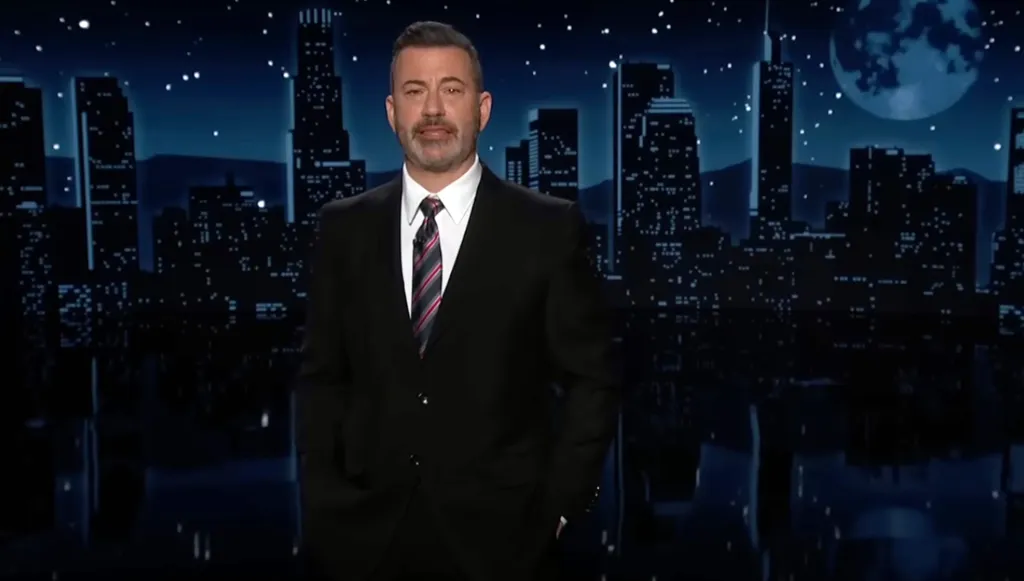 Jimmy Kimmel wearing a suit and tie on the set of Late Night.