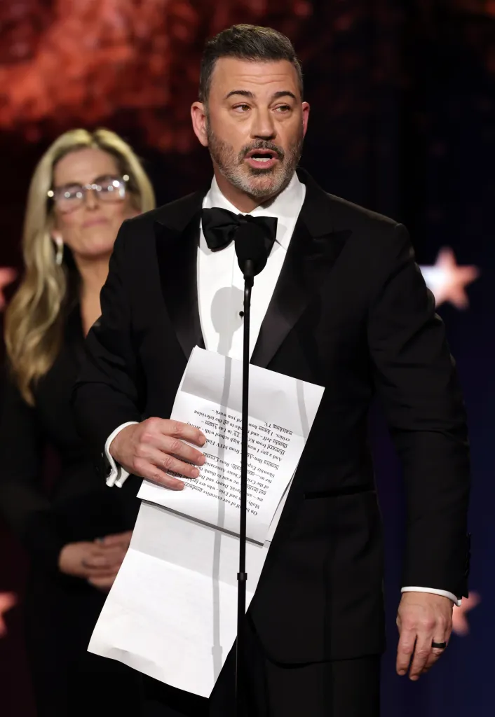 Jimmy Kimmel speaking on stage, holding notes, at the Critics Choice Awards.