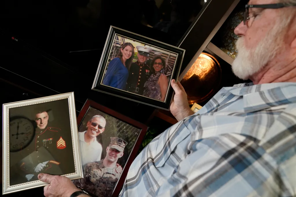Joey Reed holds photos of his son, Marine veteran Trevor Reed.