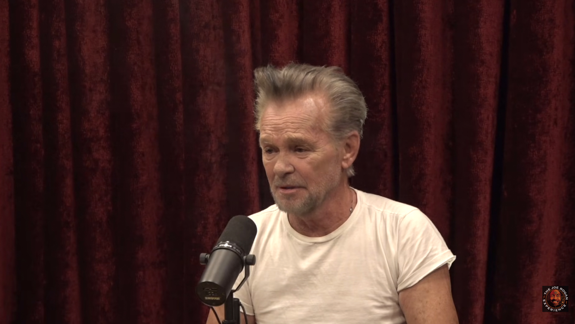 John Mellencamp speaking into a microphone on the Joe Rogan Experience podcast.