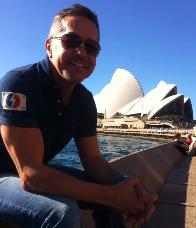 John Kaleel sitting by the water with the Sydney Opera House in the background.
