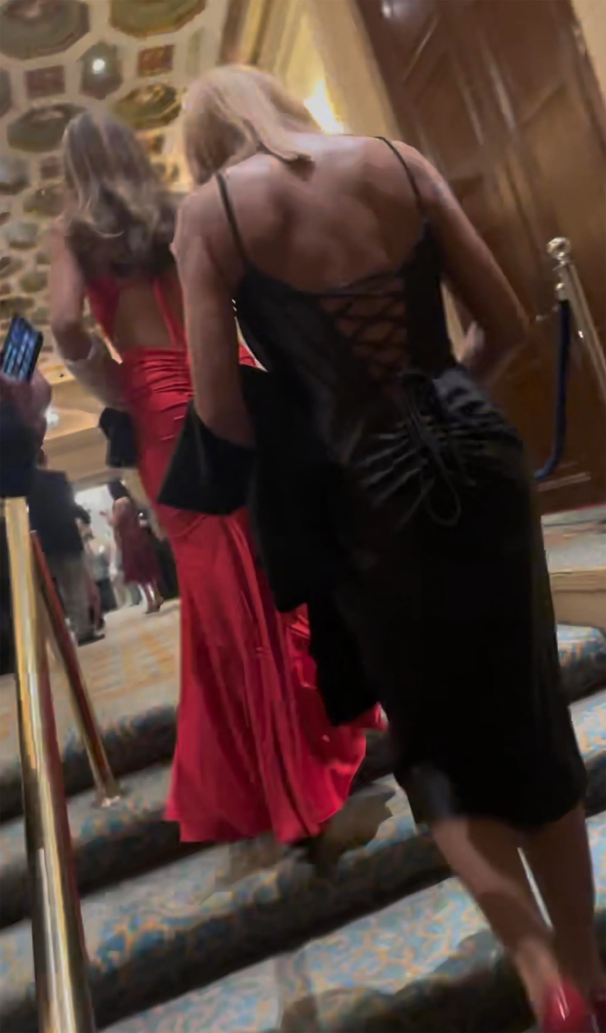 Vanessa Trump in a black dress ascending stairs, with Kai Trump in a red dress behind her.