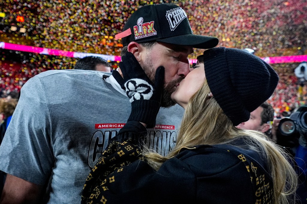 Kansas City Chiefs tight end Travis Kelce and Taylor Swift share a kiss on the field.