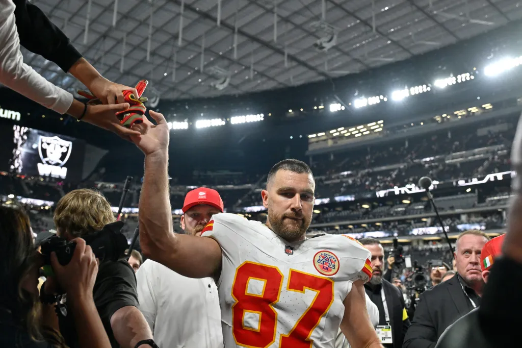 Kansas City Chiefs tight end Travis Kelce receives a gift from a fan after a game.