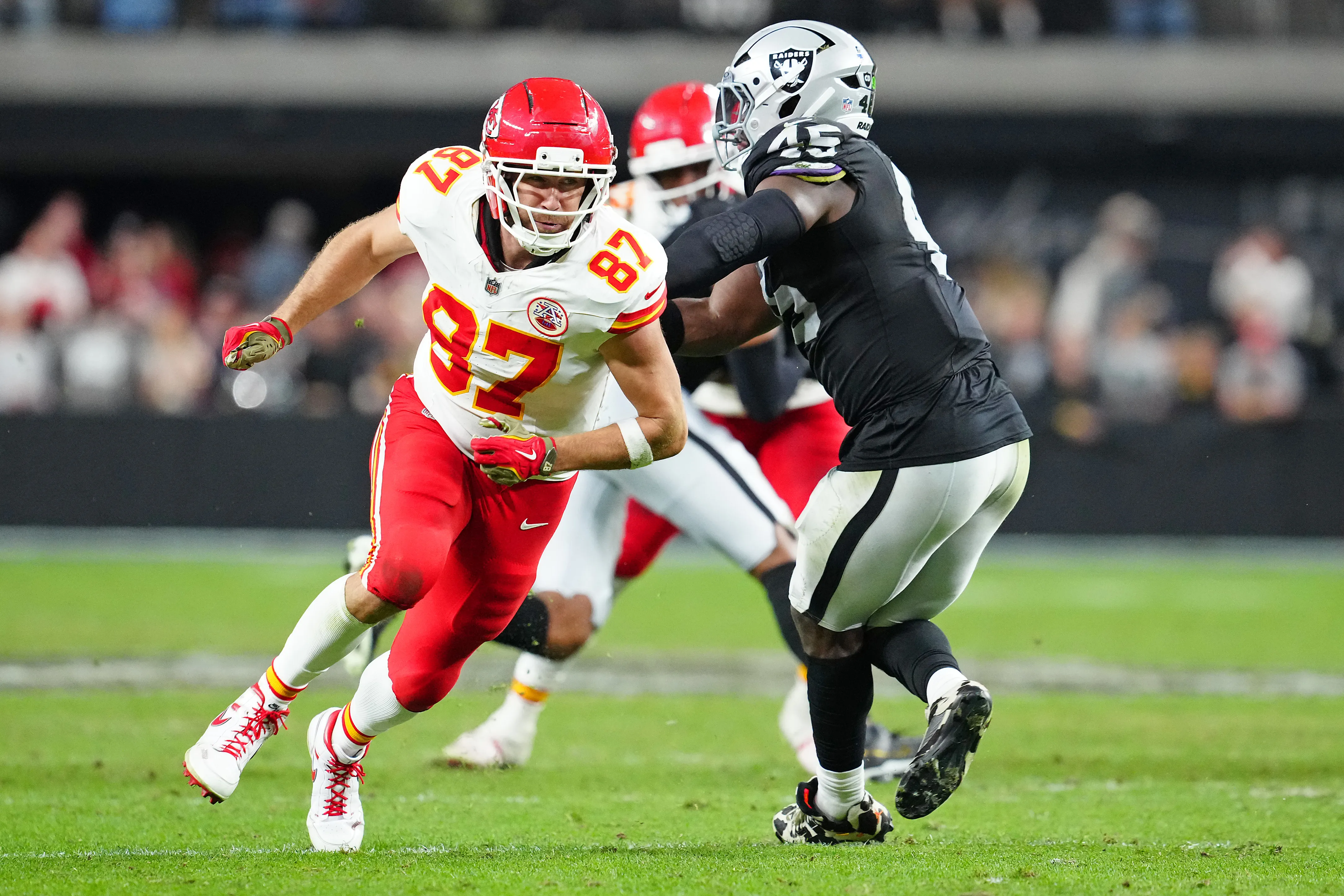 Travis Kelce (87) of the Kansas City Chiefs runs a route against a Las Vegas Raiders player.