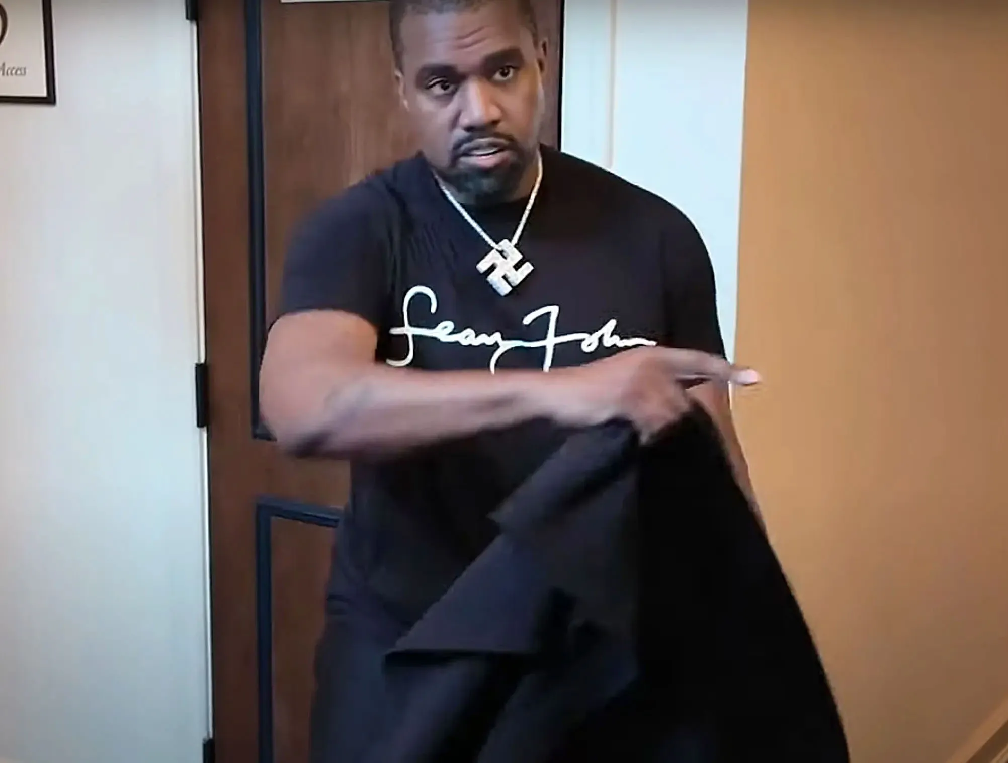 Kanye West wearing a T-shirt and a necklace with a swastika pendant.