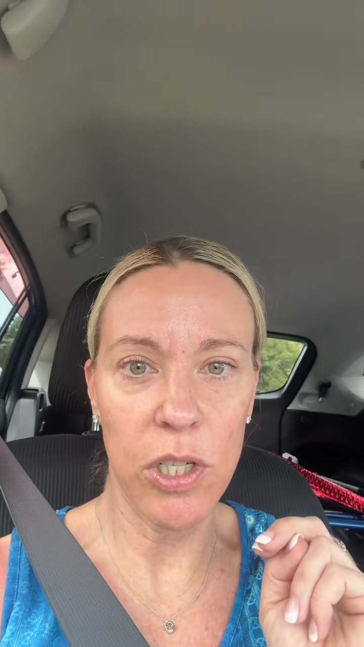 Kate Gosselin wearing a blue top, with a silver necklace, diamond earrings, and a diamond ring on her left hand while in a car.