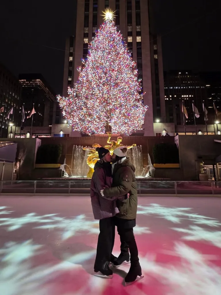 Keanu Reeves and Alexandra Grant kissing on an ice rink in front of the Rockefeller Center Christmas tree.