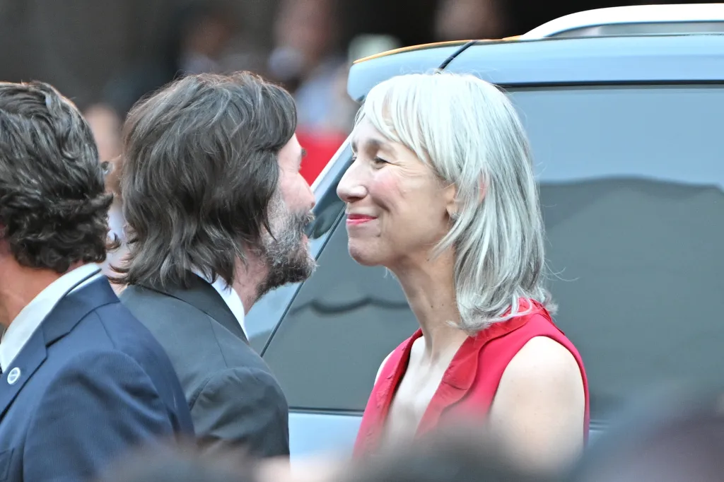 Keanu Reeves and Alexandra Grant looking at each other and smiling.