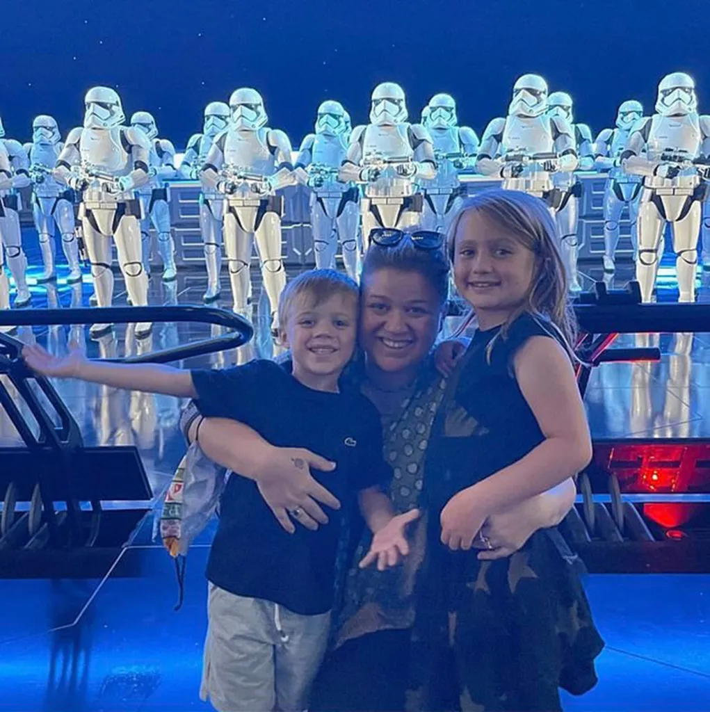 Kelly Clarkson poses with her two children in front of a line of Stormtroopers.