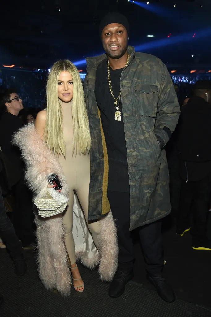Khloe Kardashian in a beige jumpsuit and Lamar Odom in a camo jacket posing together at an event.
