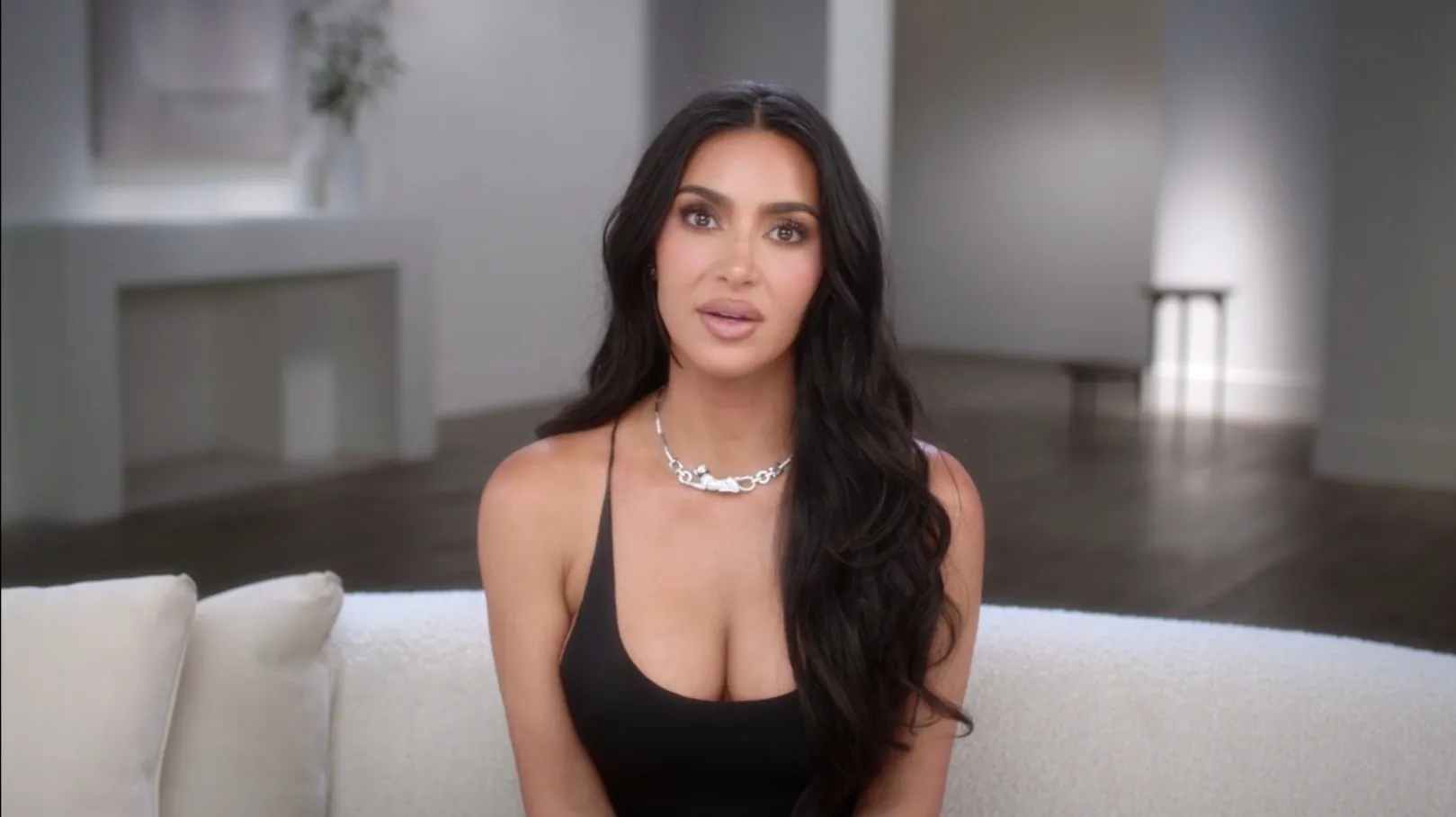 Kim Kardashian looking at the camera, wearing a black top and a silver necklace.