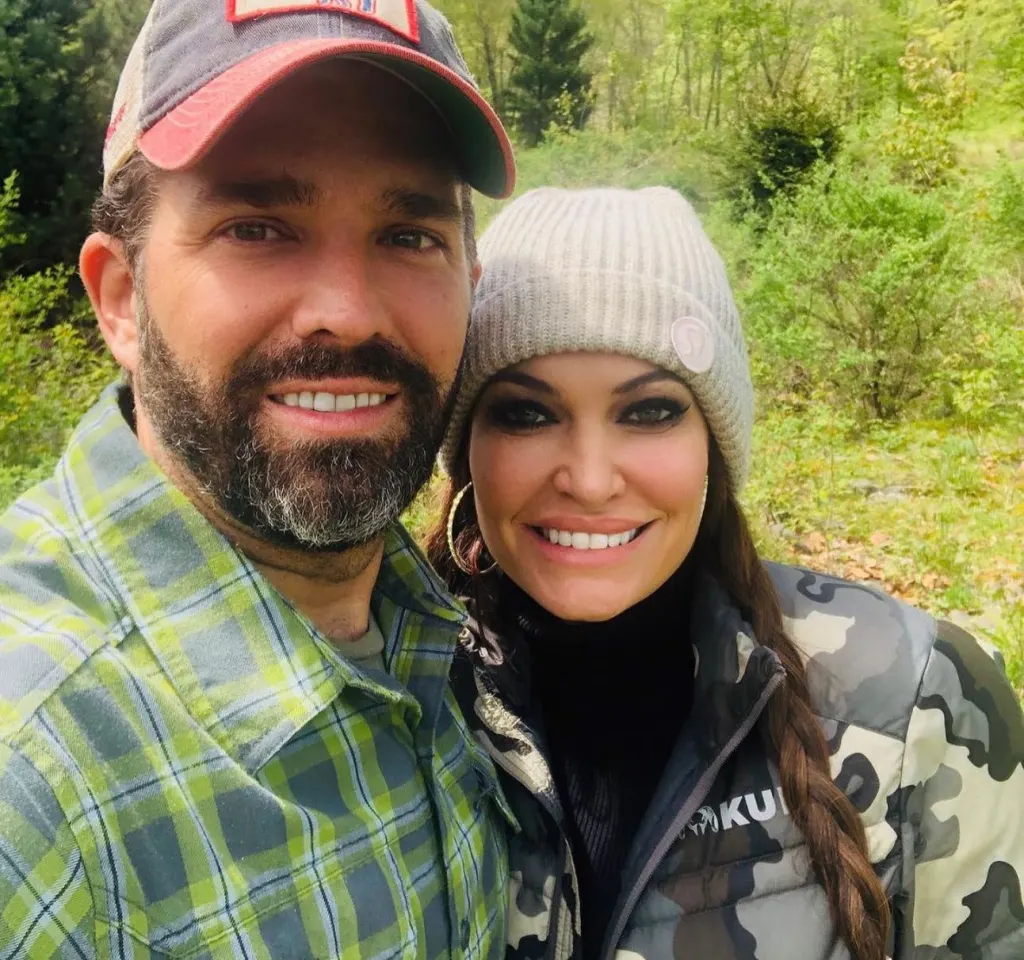 Donald Trump Jr. and Kimberly Guilfoyle smiling in outdoor attire.