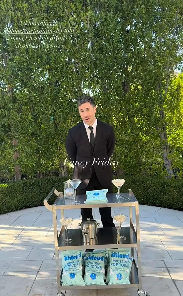 A man in a suit stands behind a bar cart with snacks and mocktails, promoting Khloé Kardashian's sobriety.