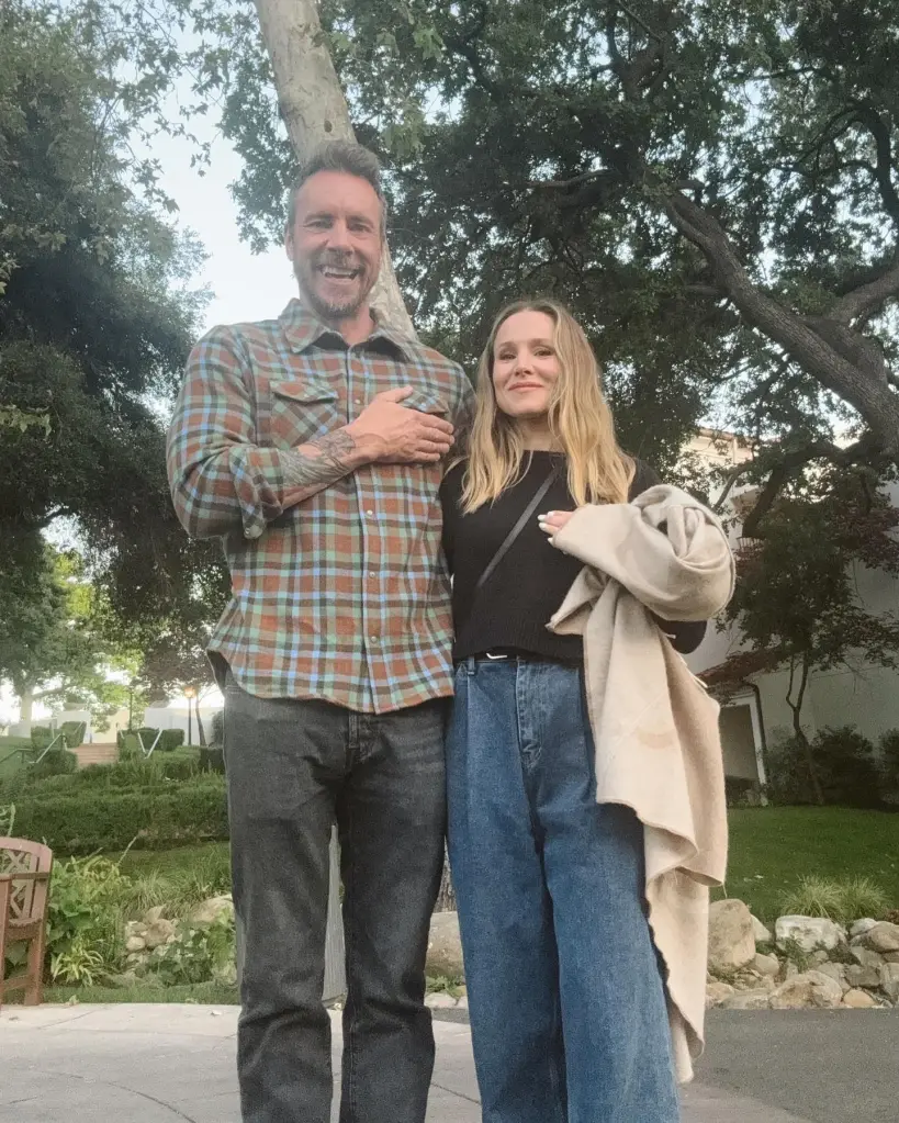 Kristen Bell and Dax Shepard standing outside with hands over their hearts.
