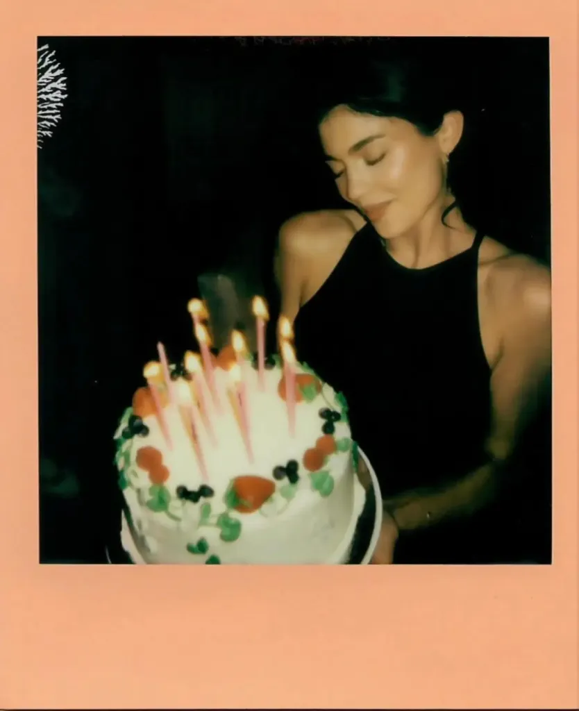 Kylie Jenner holding her birthday cake with candles lit.
