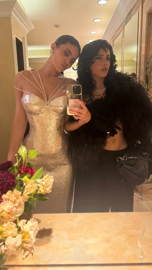 Kylie Jenner and another woman taking a mirror selfie.