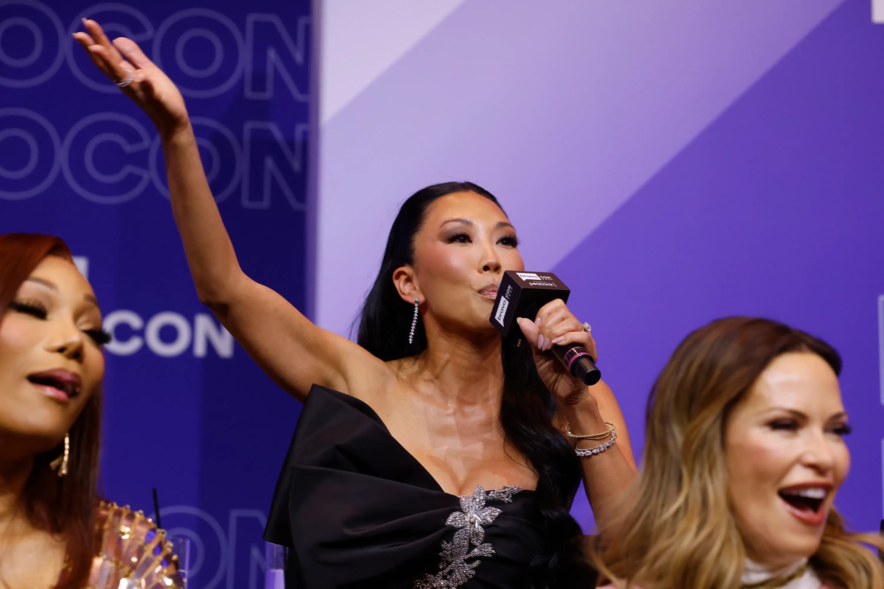 Katie Ginella holding a BravoCon microphone, with Angela Oakley and Britany Batemen beside her.