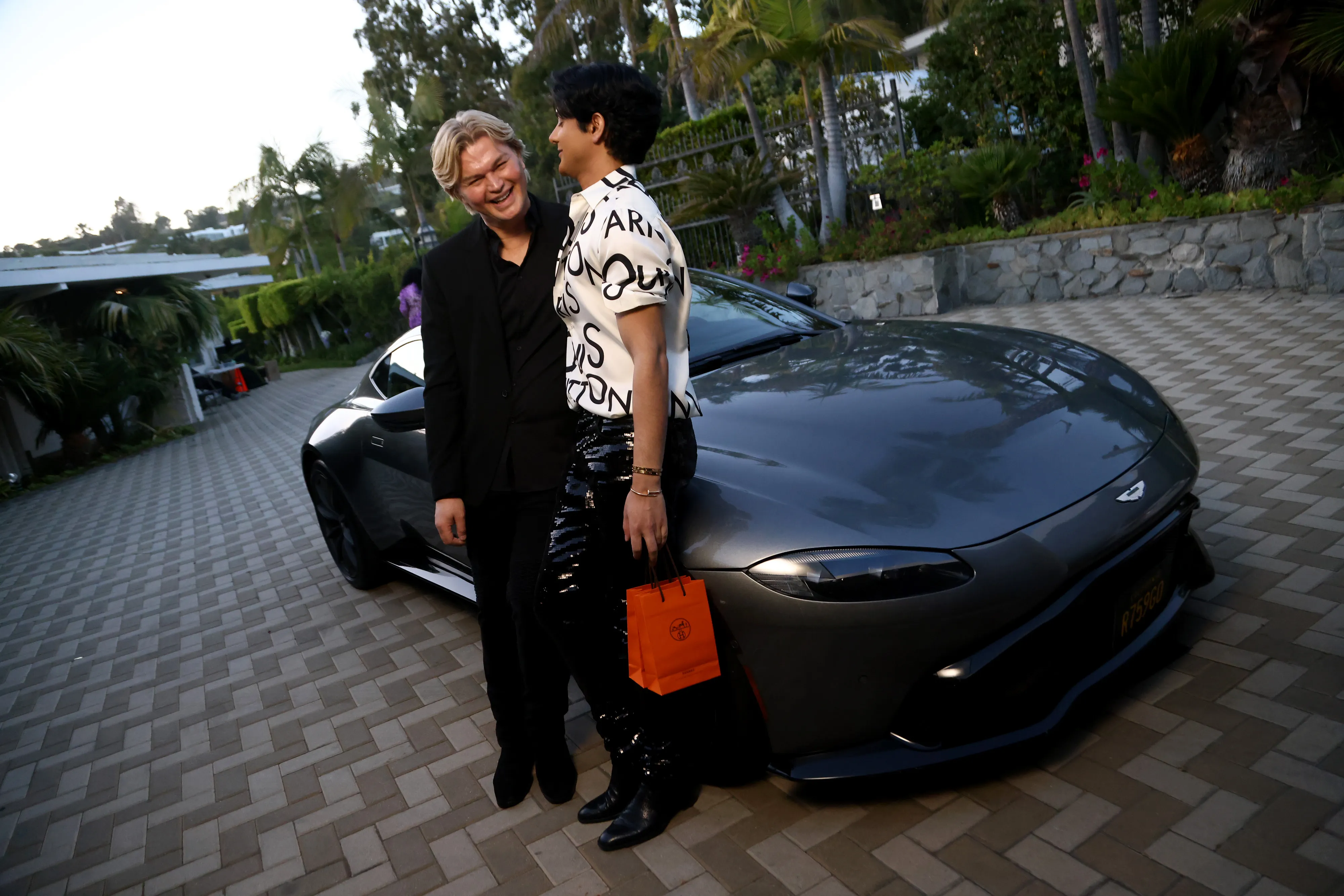 Kim Vo and Adeel Khan posing in front of a gray sports car.