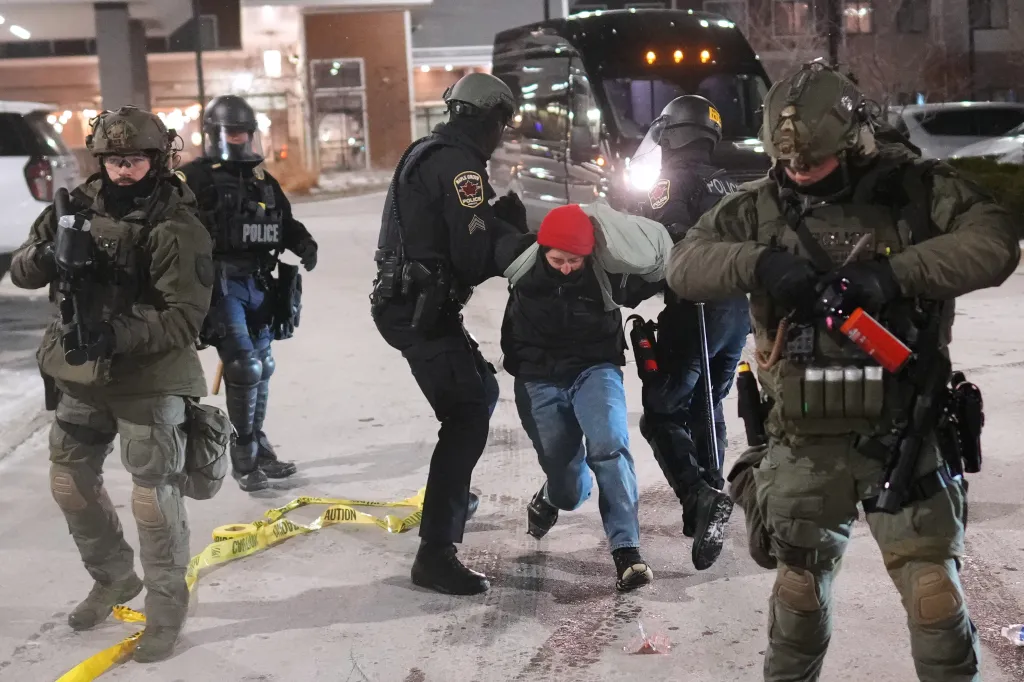 Law enforcement officers detain a demonstrator during a protest outside SpringHill Suites and Residence Inn by Marriott hotels on Monday, Jan. 26, 2026, in Maple Grove, Minn.